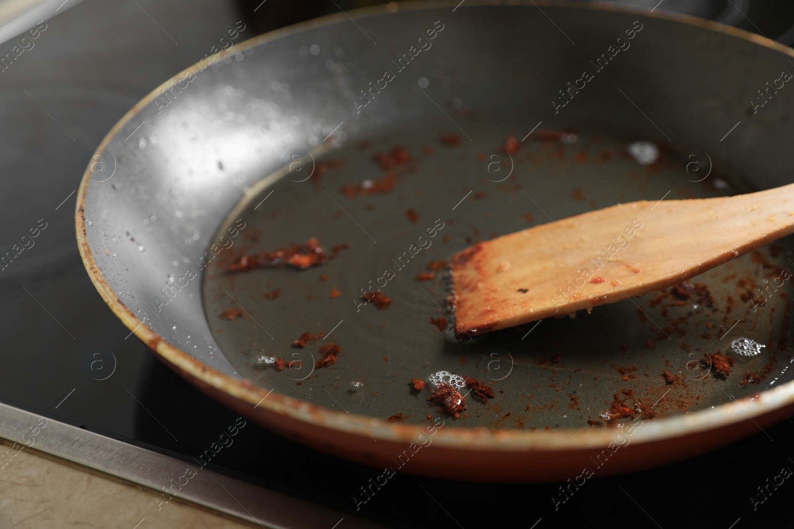 Photo of Frying pan with spatula and used cooking oil on stove, closeup