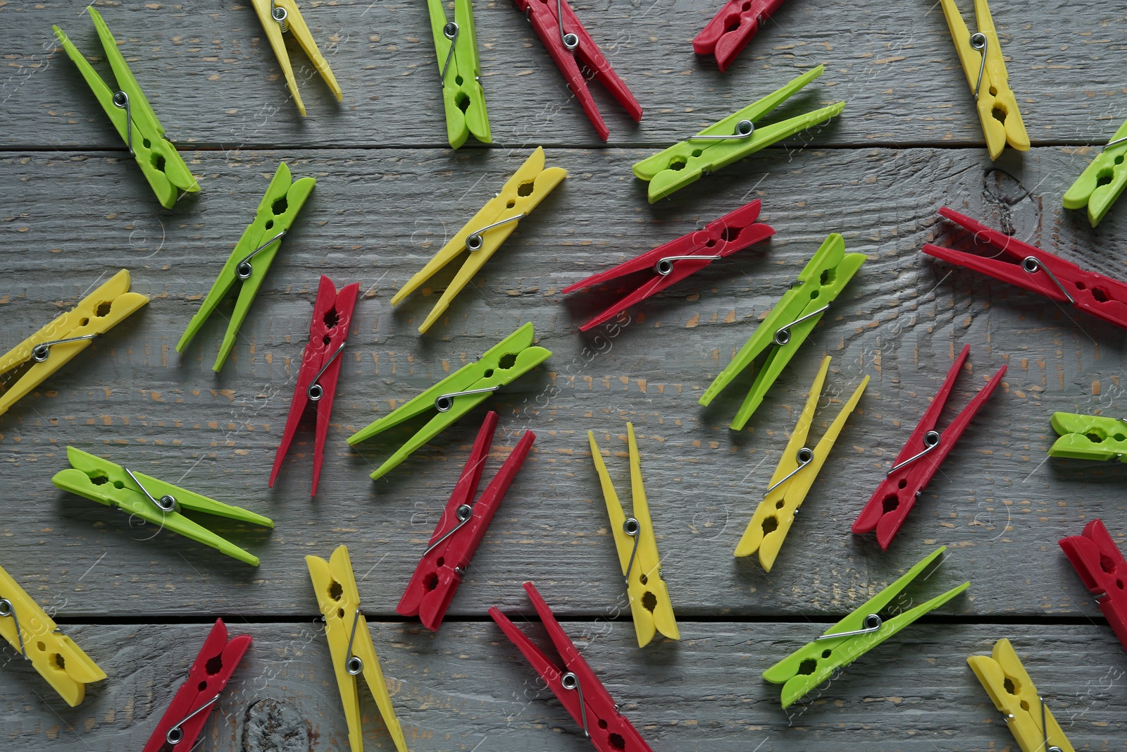 Photo of Colorful plastic clothespins on grey wooden background, flat lay