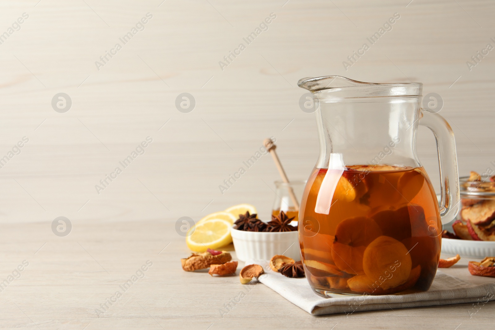 Photo of Delicious compote with dried fruits in glass jug on light wooden table, space for text
