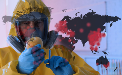 Image of Scientist in chemical protective suit with apple and syringe at laboratory. Vaccine research