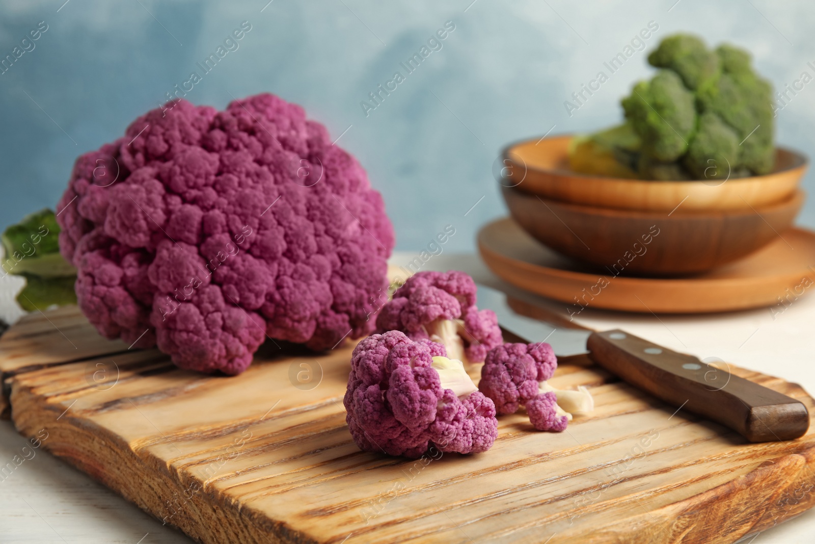 Photo of Wooden board with purple cauliflower cabbage on table. Healthy food