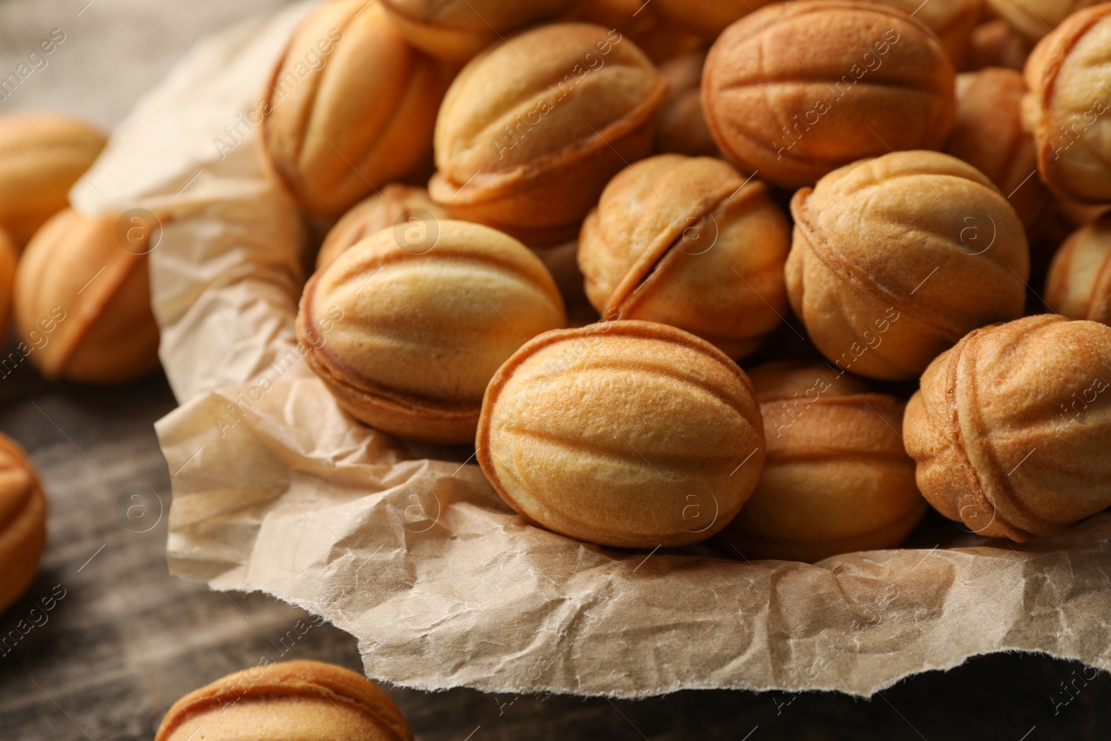 Photo of Bowl of delicious nut shaped cookies on wooden table, closeup