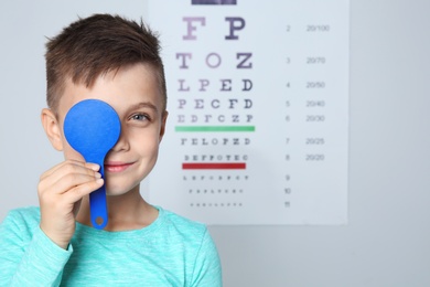 Photo of Cute little boy visiting children's doctor, space for text. Eye examination