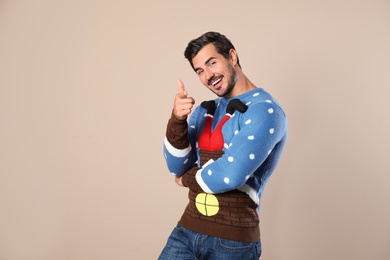 Photo of Portrait of happy man in Christmas sweater on beige background