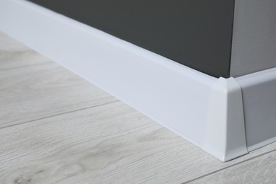 Photo of White plinth with connector on laminated floor near black wall indoors, closeup