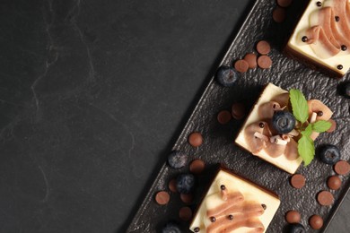 Photo of Pieces of triple chocolate mousse cake on black table, top view with space for text