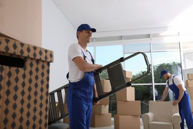 Moving service employees with ladder and cardboard boxes in room