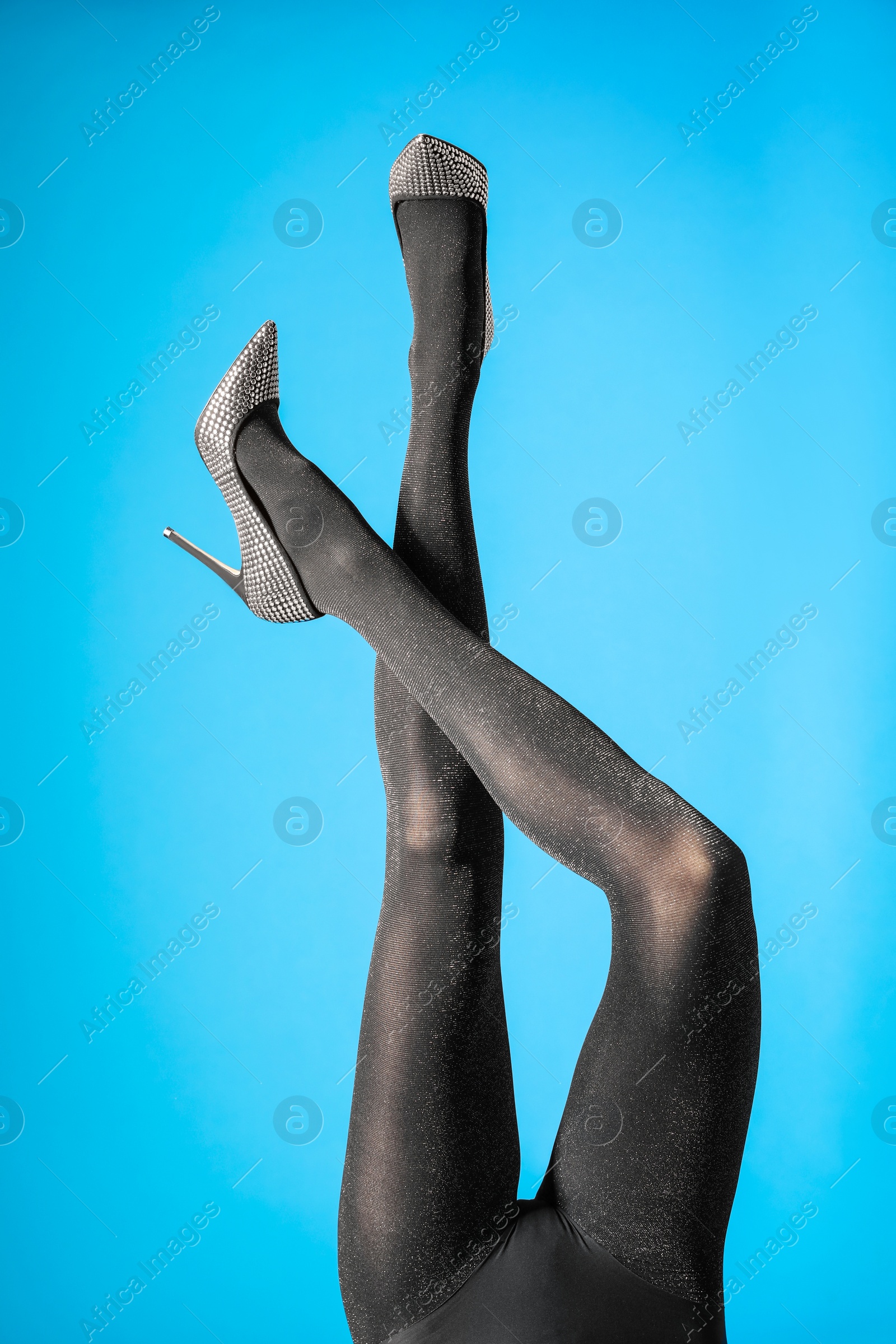 Photo of Woman wearing black tights and stylish shoes on blue background, closeup of legs