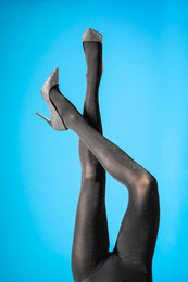 Woman wearing black tights and stylish shoes on blue background, closeup of legs