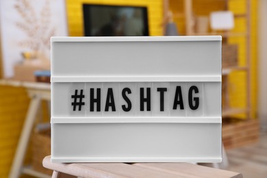 Photo of Light box with symbol and word Hashtag on wooden table indoors