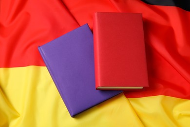 Photo of Learning foreign language. Different books on flag of Germany, top view