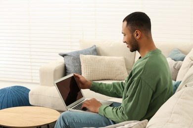 Photo of African American man working on laptop at home