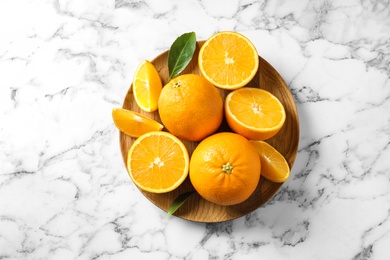 Photo of Plate with ripe oranges on marble background, top view