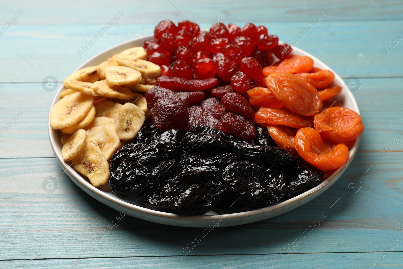 Photo of Delicious dried fruits on light blue wooden table