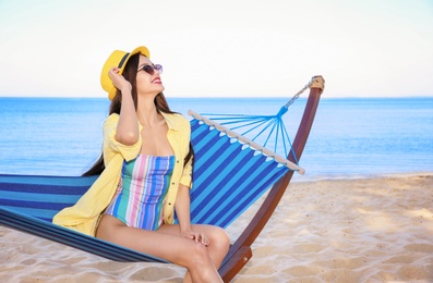 Photo of Young woman sitting in hammock at seaside. Summer vacation