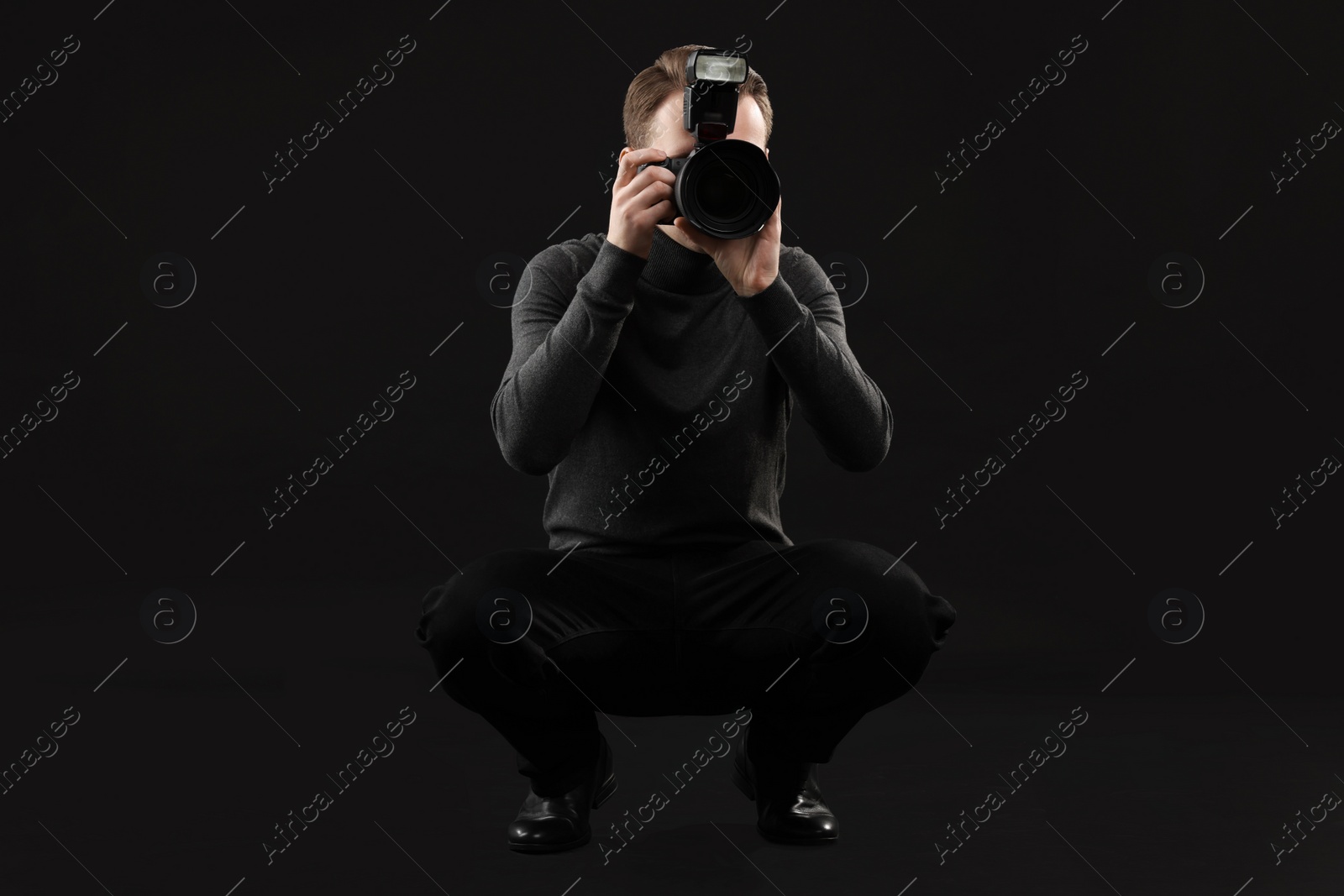 Photo of Professional photographer taking picture on black background