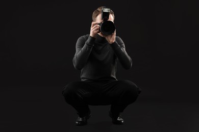 Photo of Professional photographer taking picture on black background