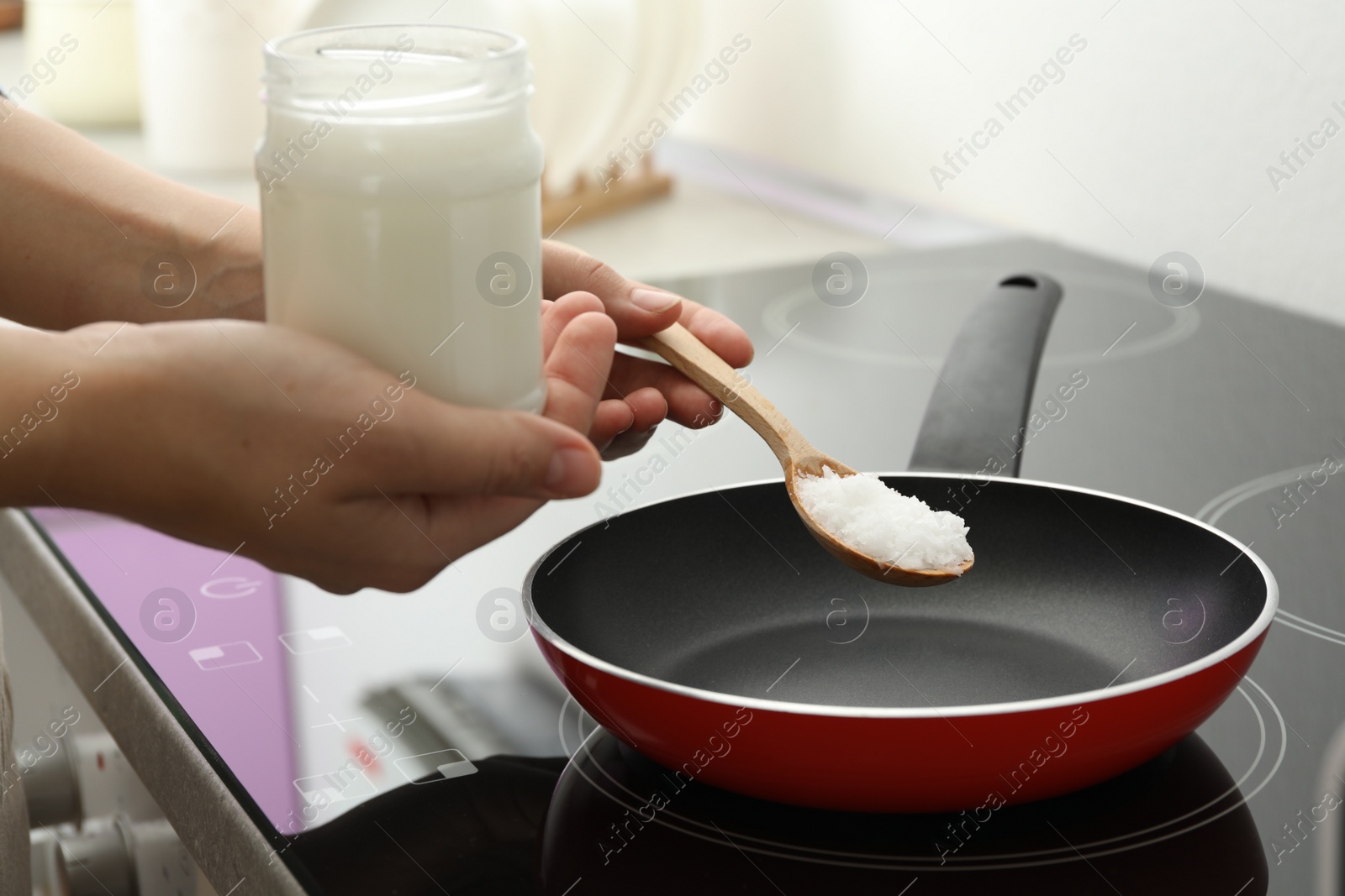 Photo of Woman cooking with coconut oil on induction stove, closeup