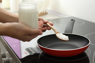 Photo of Woman cooking with coconut oil on induction stove, closeup