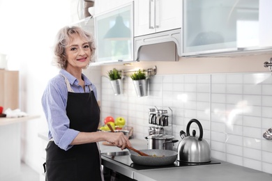 Photo of Professional female chef cooking vegetables in kitchen