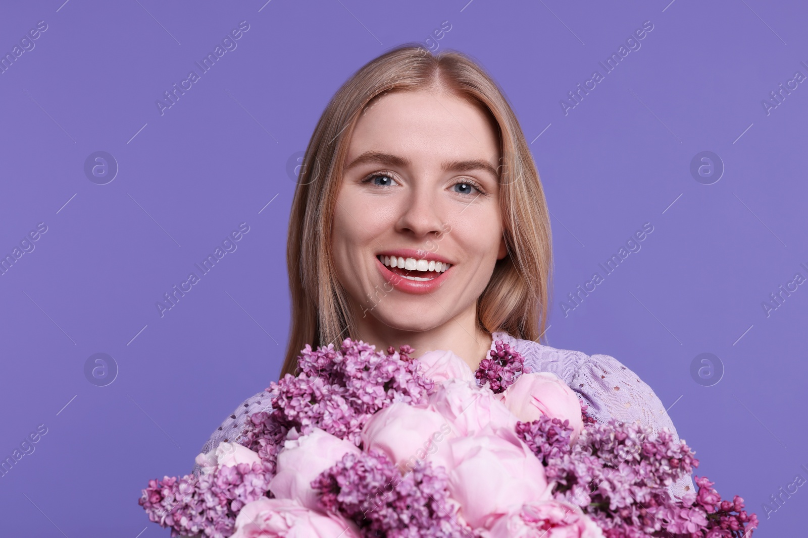 Photo of Beautiful woman with bouquet of spring flowers on purple background