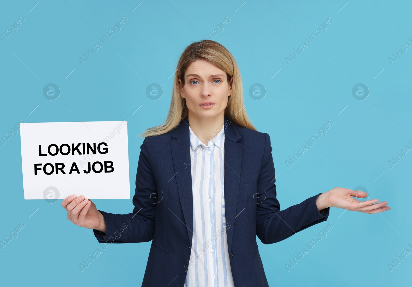 Photo of Unemployed woman holding sign with phrase Looking For A Job on light blue background