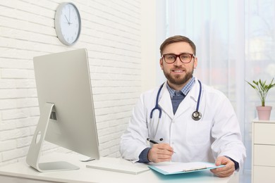 Portrait of pediatrician at table in clinic
