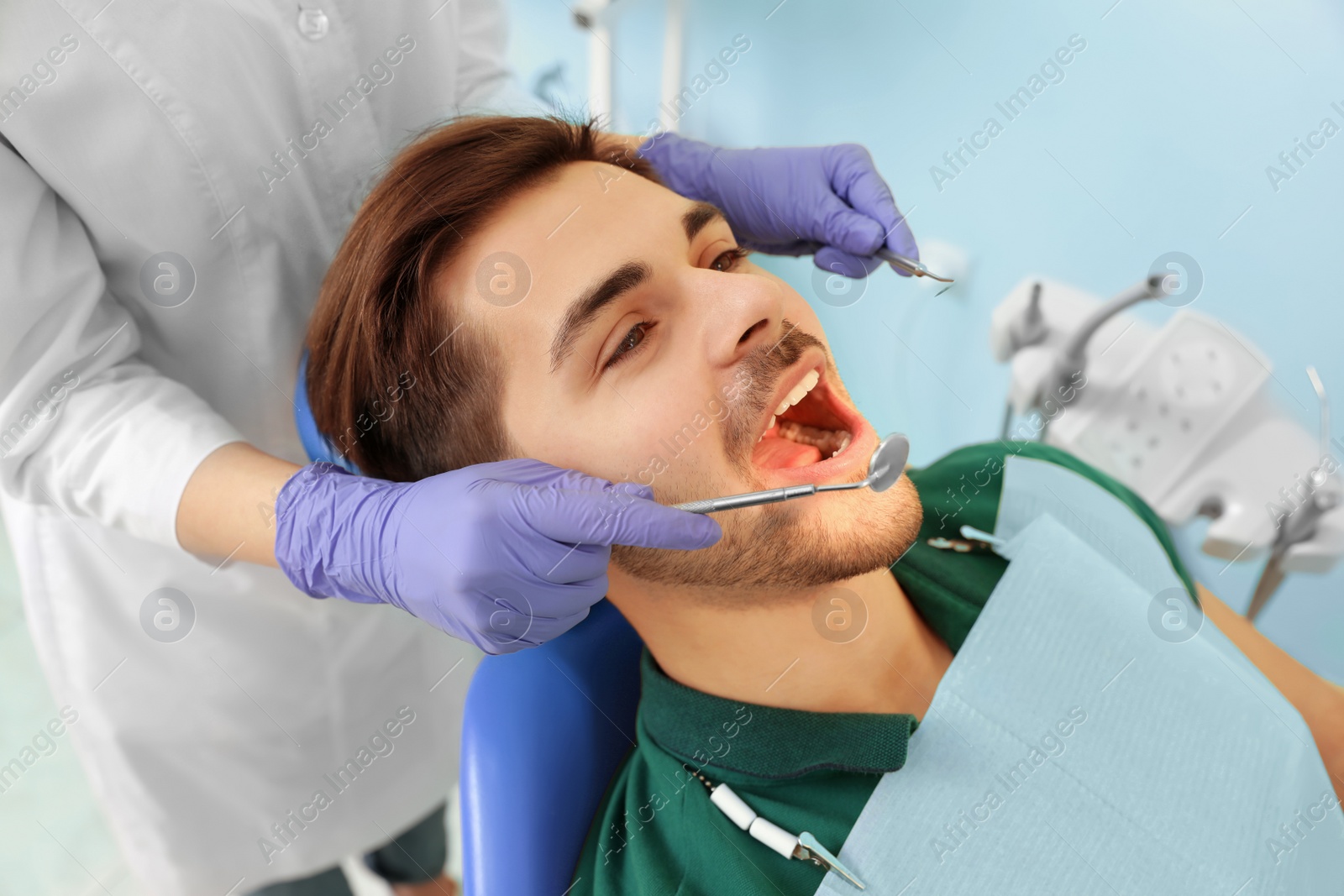 Photo of Professional dentist working with patient in modern clinic