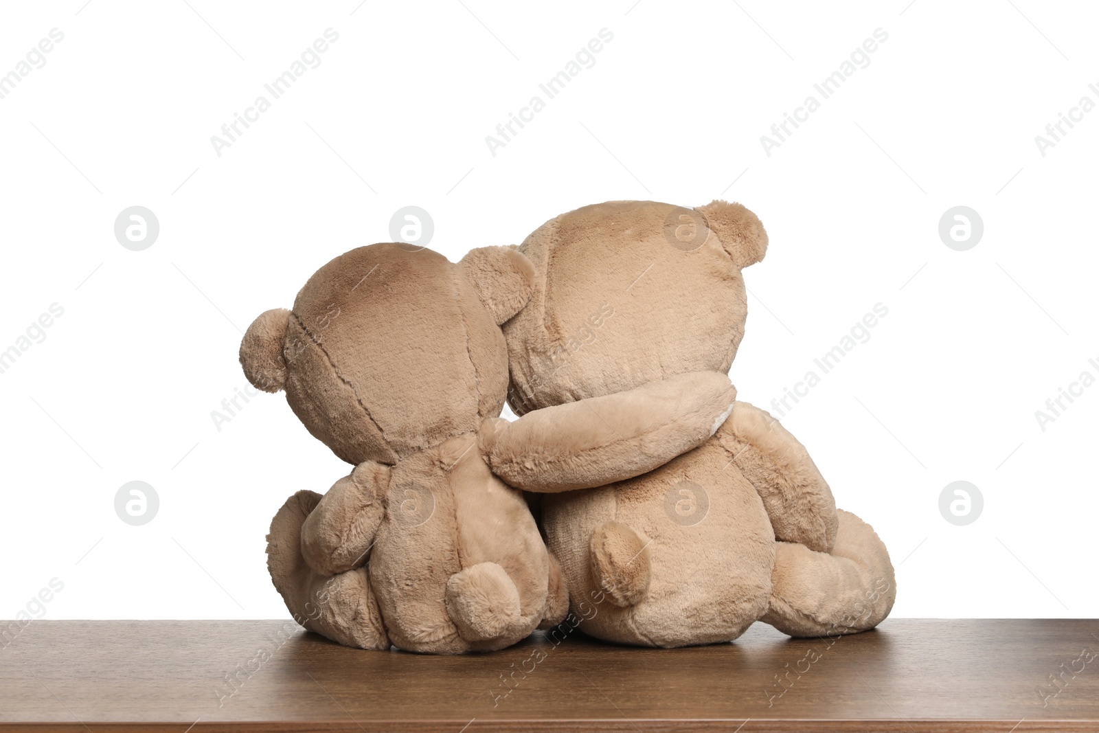 Photo of Cute teddy bears on wooden table against white background, back view