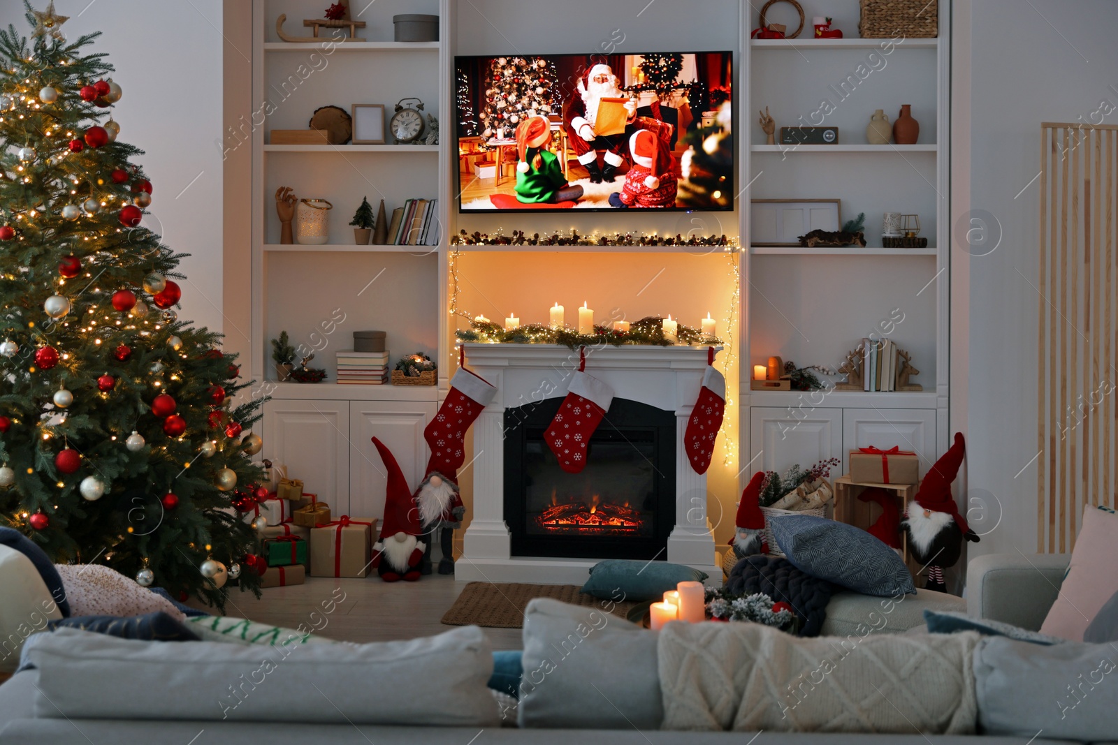 Photo of TV set with Christmas movie above fireplace in cosy room. Winter holidays atmosphere