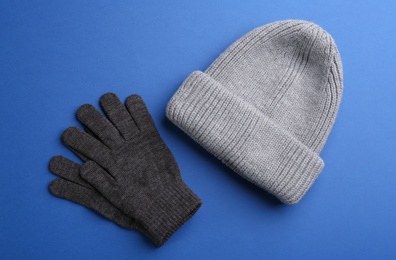 Photo of Woolen gloves and hat on blue background, flat lay