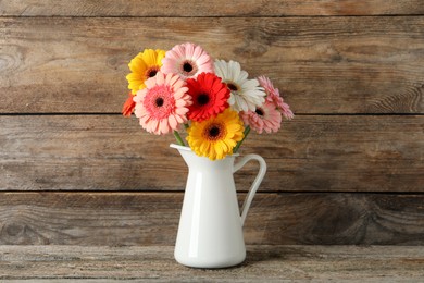 Bouquet of beautiful colorful gerbera flowers in vase on wooden table