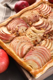 Photo of Tasty apple pie with nuts and fresh fruits on table, closeup