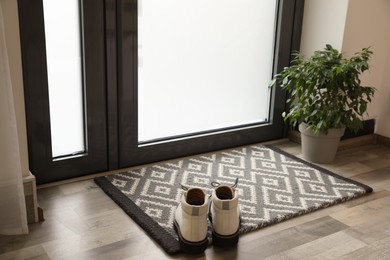 Photo of Stylish boots on door mat in hall