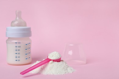 Powdered infant formula with scoop and feeding bottle on pink background, space for text. Baby milk