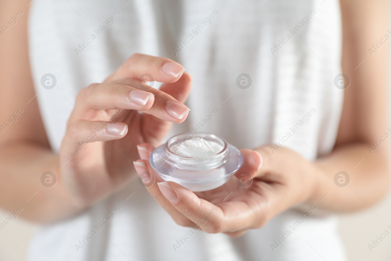 Photo of Young woman holding glass jar of cream, closeup