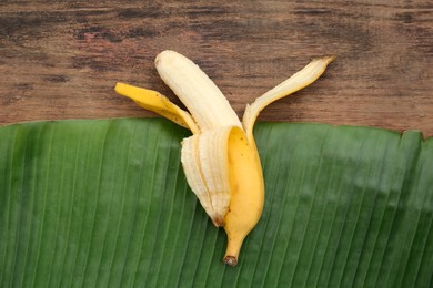 One delicious banana and fresh leaf on wooden table, top view