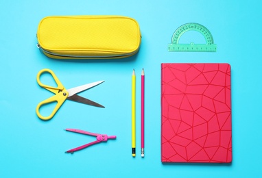 Flat lay composition with scissors and school stationery on light blue background