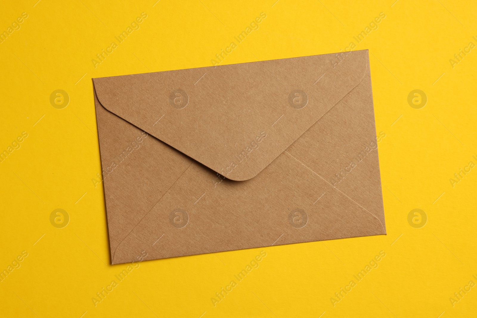 Photo of Envelope made of parchment paper on yellow background, top view