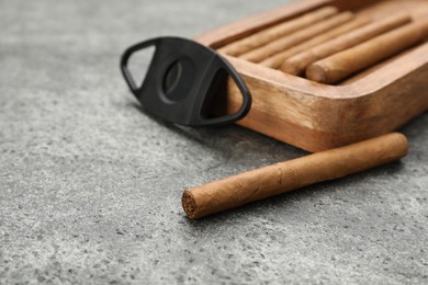 Photo of Cigars and guillotine cutter on grey table. Space for text