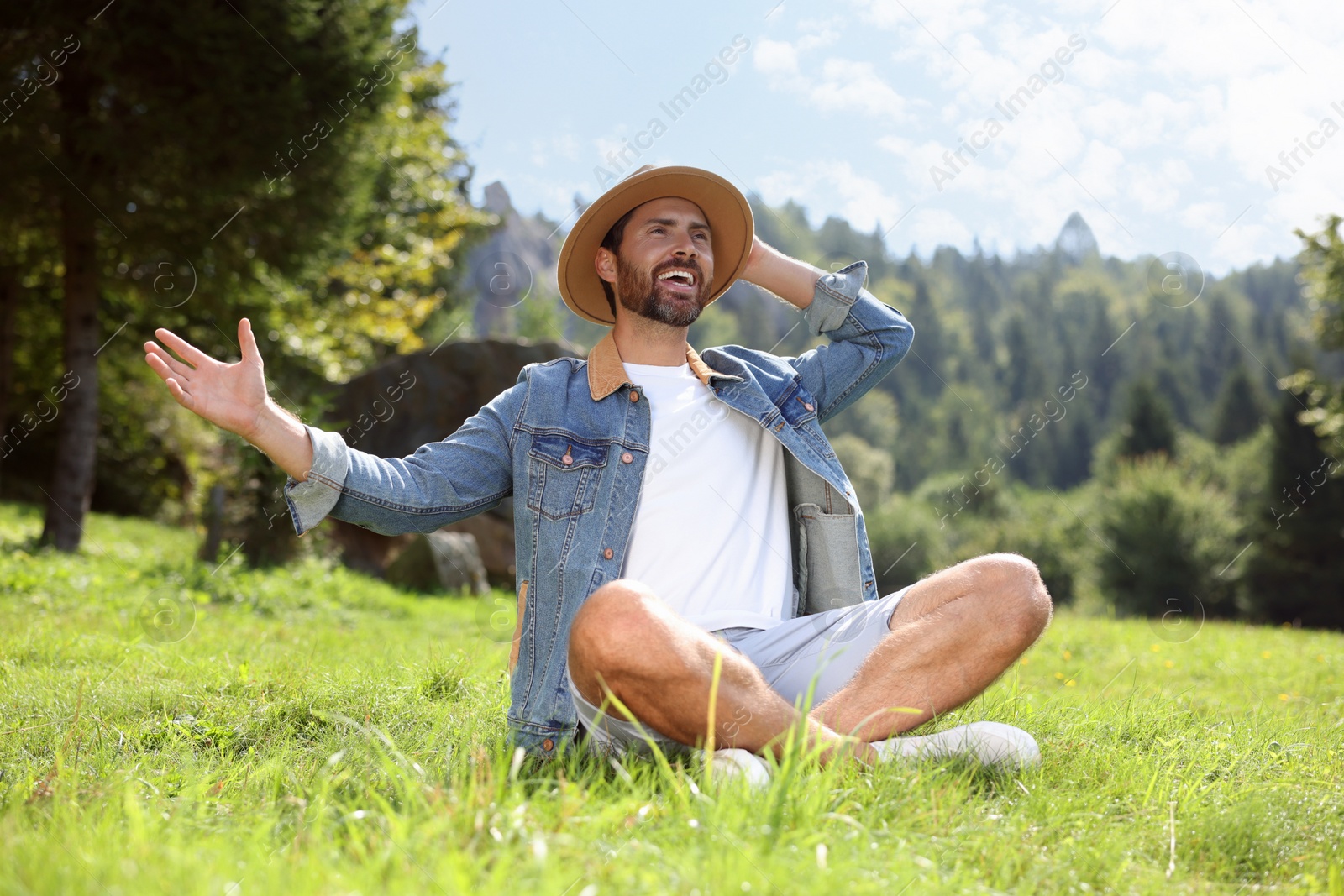 Photo of Feeling freedom. Smiling man enjoying nature on green grass outdoors