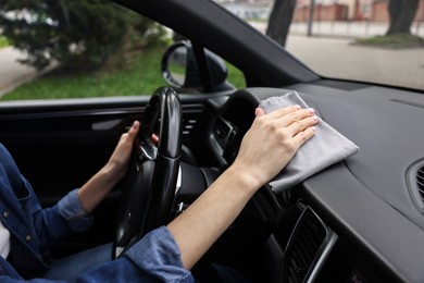 Woman wiping her modern car with rag, closeup