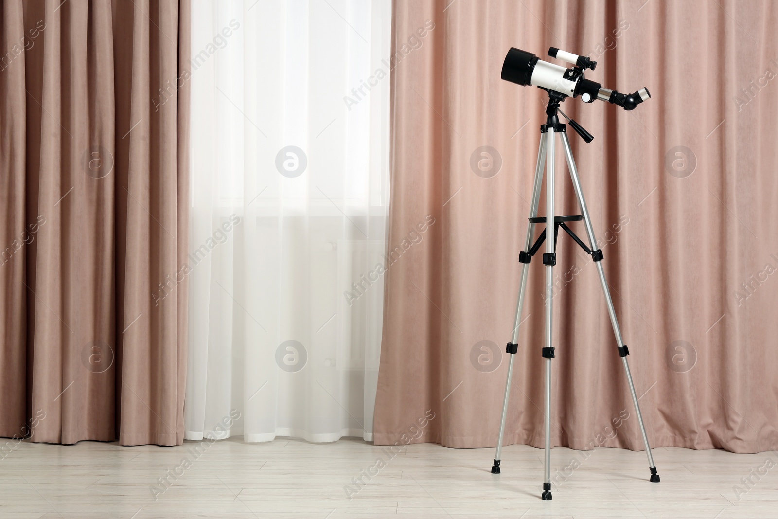 Photo of Tripod with modern telescope in stylish room. Space for text