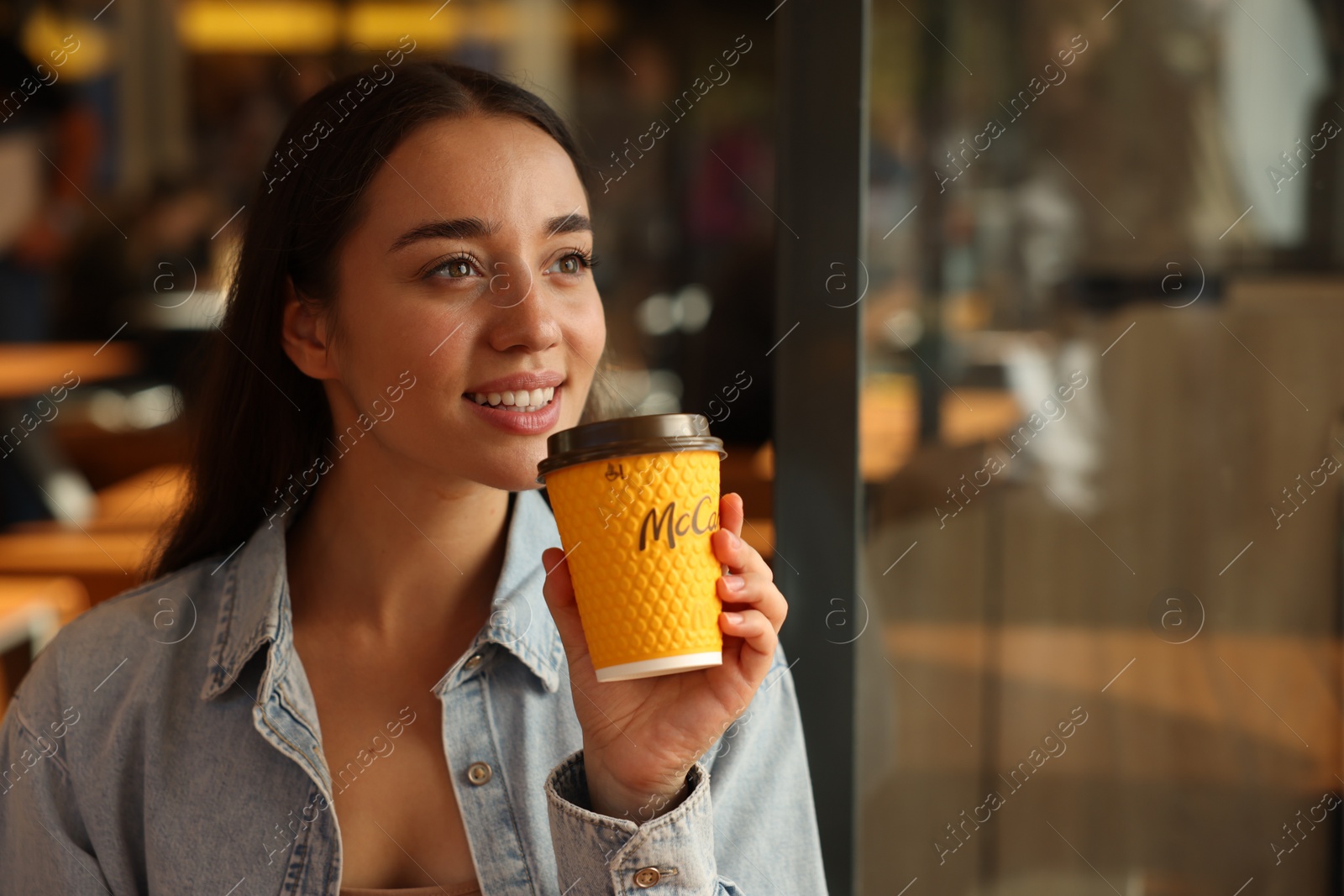 Photo of Lviv, Ukraine - September 26, 2023: Woman with hot McDonald's drink in cafe, space for text