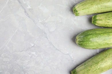 Photo of Fresh ripe zucchini on grey marble background, flat lay. space for text