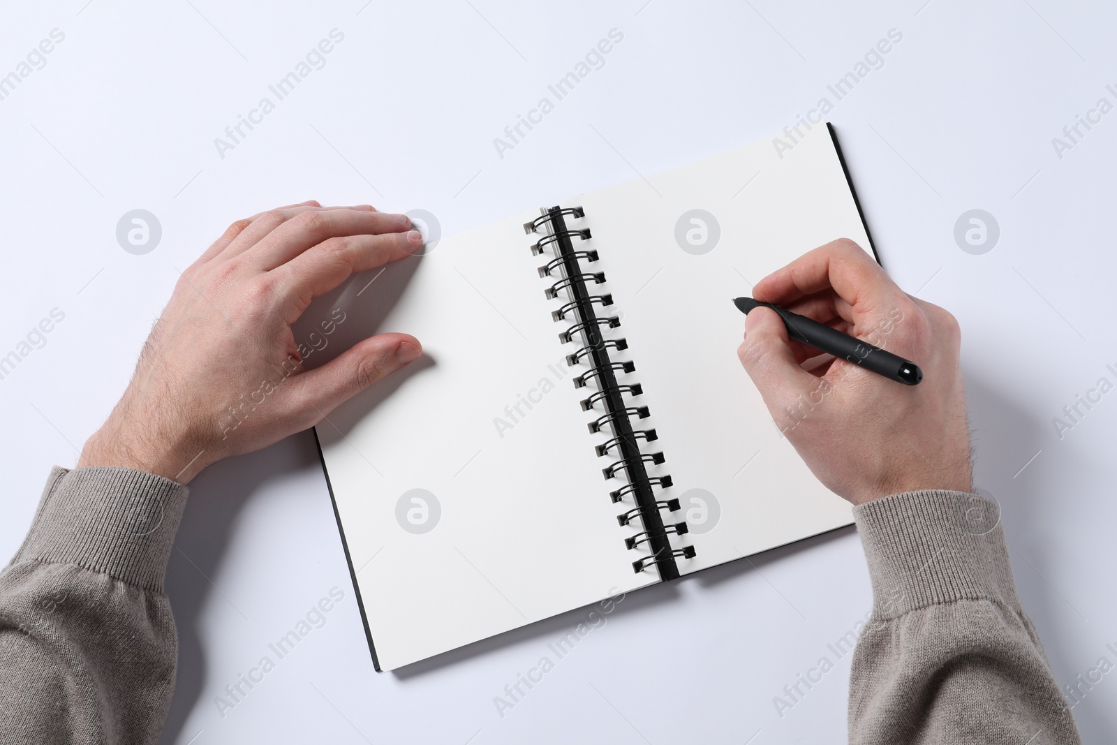 Photo of Man with pen and empty notepad on white background, top view