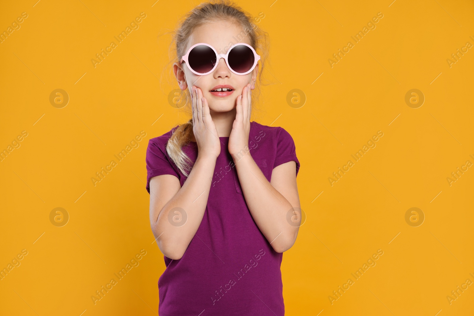 Photo of Emotional girl in stylish sunglasses on orange background