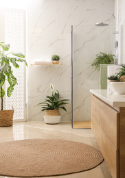 Stylish bathroom interior with countertop, shower stall and houseplants. Design idea