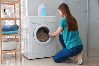 Woman near washing machine in bathroom. Laundry day