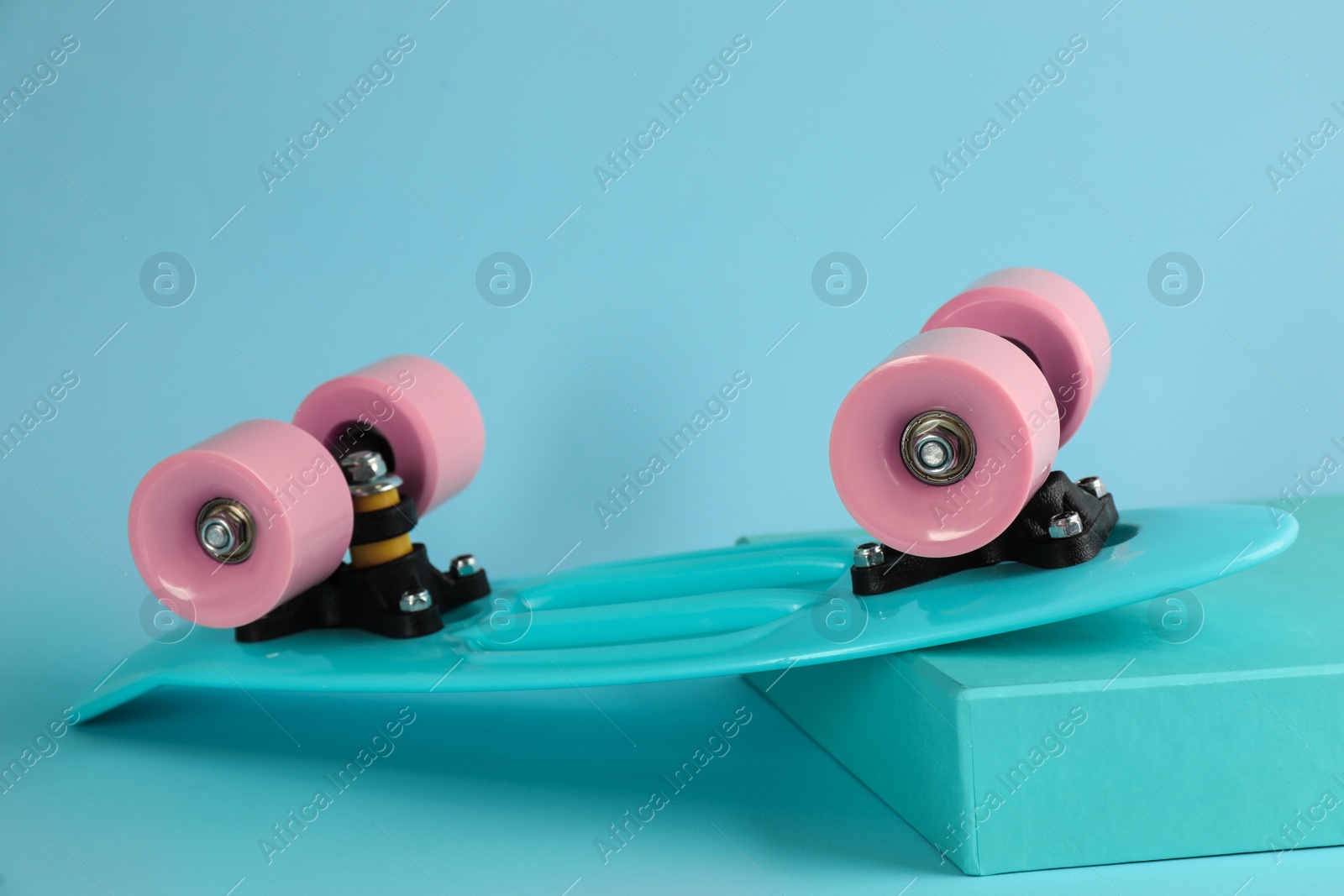 Photo of Turquoise skateboard on light blue background. Sport equipment